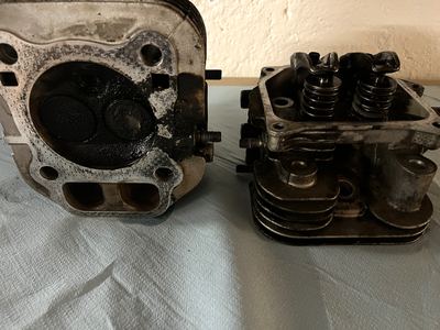Zwei Zylinderköpfe vor der Reinigung, mit Ölkohle und Ölresten